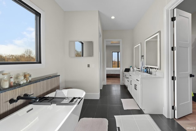 bathroom with a soaking tub, ensuite bathroom, vanity, baseboards, and tile patterned floors