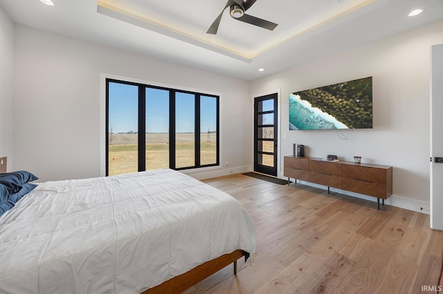 bedroom featuring recessed lighting, a ceiling fan, baseboards, light wood finished floors, and a raised ceiling