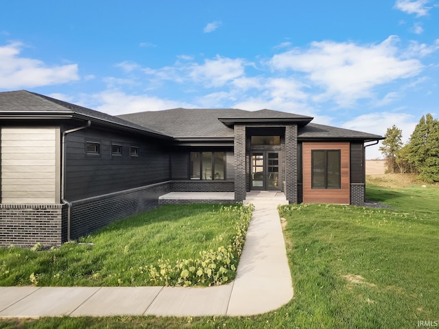 prairie-style home with brick siding, a front lawn, and a shingled roof