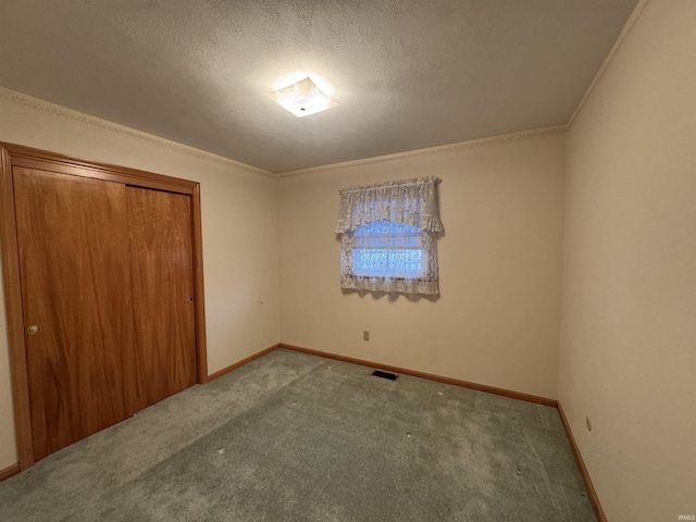 unfurnished bedroom with a textured ceiling, ornamental molding, carpet, and baseboards