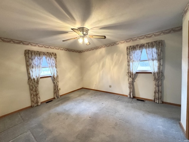 carpeted spare room with a ceiling fan, visible vents, and baseboards