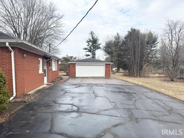 view of property exterior featuring a garage, an outbuilding, and brick siding