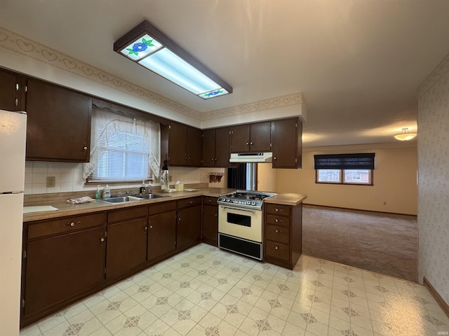 kitchen featuring light countertops, dark brown cabinetry, a sink, range, and under cabinet range hood