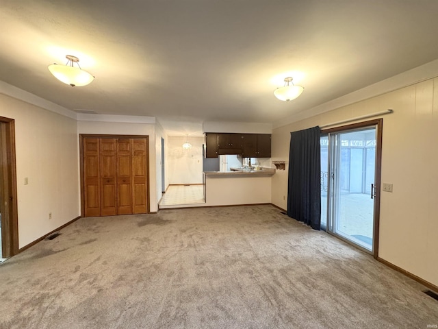 unfurnished living room featuring light carpet, visible vents, baseboards, and crown molding