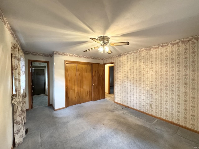 unfurnished bedroom featuring carpet floors, a closet, ceiling fan, baseboards, and wallpapered walls