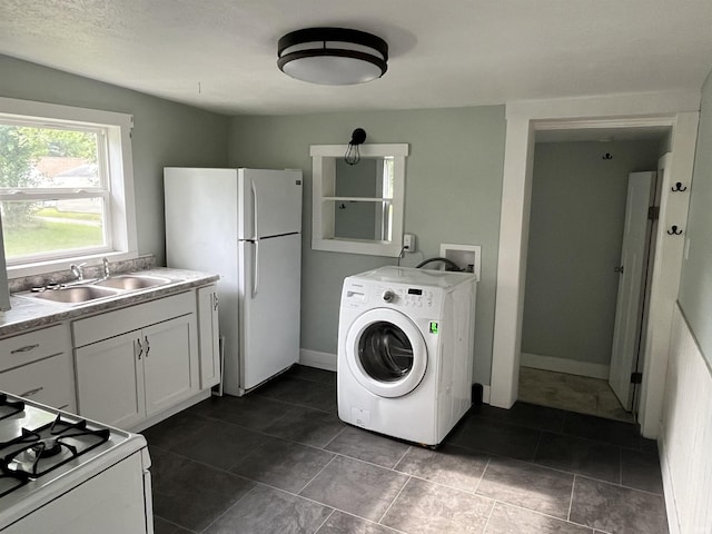 clothes washing area featuring laundry area, baseboards, washer / clothes dryer, and a sink