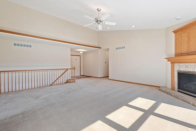 unfurnished living room with light carpet, ceiling fan, visible vents, and a tiled fireplace