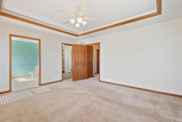 unfurnished bedroom featuring a tray ceiling, light colored carpet, connected bathroom, and baseboards