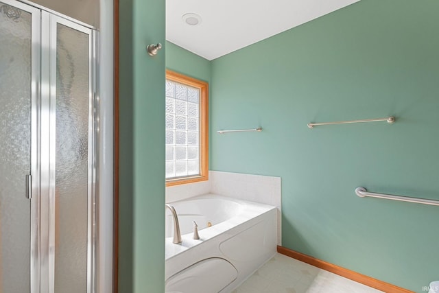 full bath featuring a garden tub, a shower stall, and baseboards