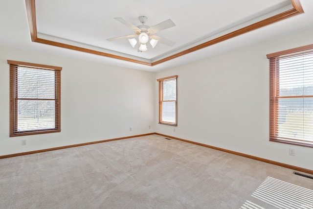 empty room featuring light carpet, baseboards, and a tray ceiling