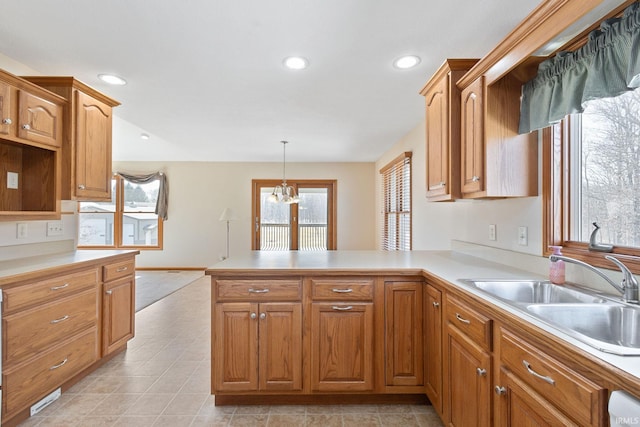 kitchen with light countertops, hanging light fixtures, a peninsula, and a sink