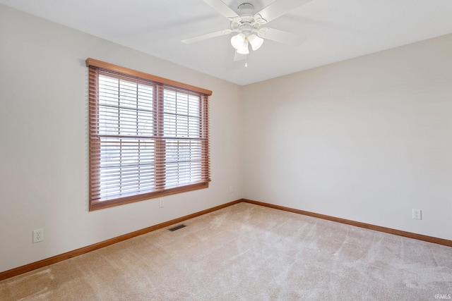 spare room with light carpet, baseboards, visible vents, and ceiling fan