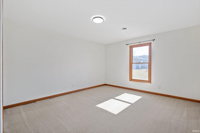 empty room featuring light colored carpet and baseboards