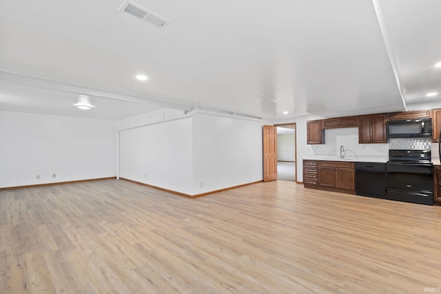 kitchen featuring a sink, visible vents, light countertops, light wood-type flooring, and black appliances