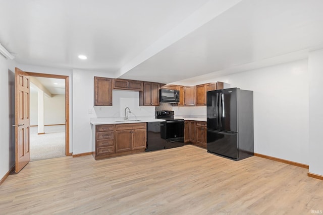 kitchen featuring light wood-type flooring, black appliances, baseboards, and light countertops