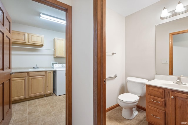 bathroom with toilet, two vanities, a sink, and washer / dryer