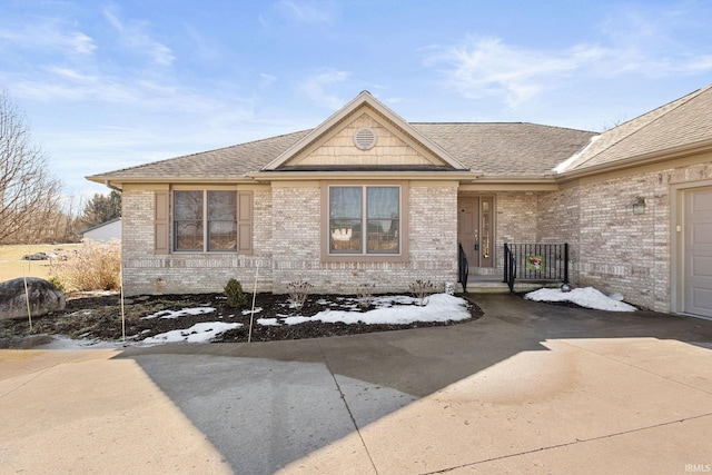 view of front of house featuring a garage, concrete driveway, brick siding, and roof with shingles