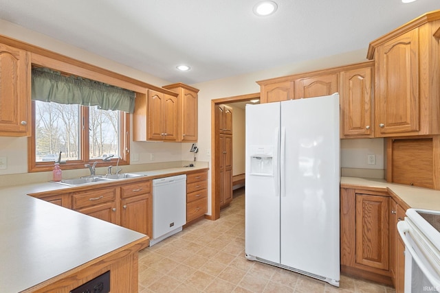 kitchen featuring white appliances, light countertops, a sink, and recessed lighting