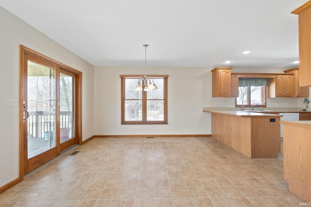 kitchen with a peninsula, baseboards, light countertops, hanging light fixtures, and an inviting chandelier