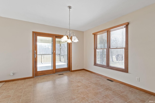 spare room featuring an inviting chandelier, baseboards, and visible vents