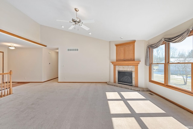 unfurnished living room with lofted ceiling, a fireplace, visible vents, and light colored carpet