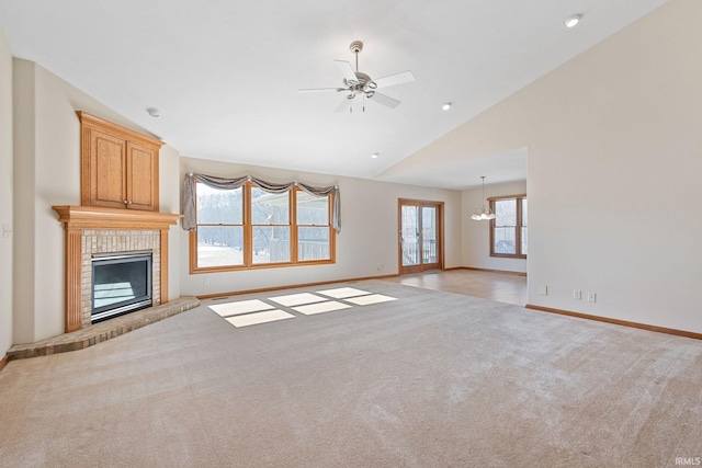 unfurnished living room with a fireplace, light colored carpet, vaulted ceiling, baseboards, and ceiling fan with notable chandelier