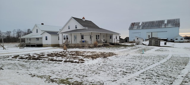 snow covered back of property featuring a porch