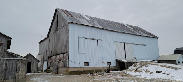 snow covered structure featuring an outdoor structure and a barn