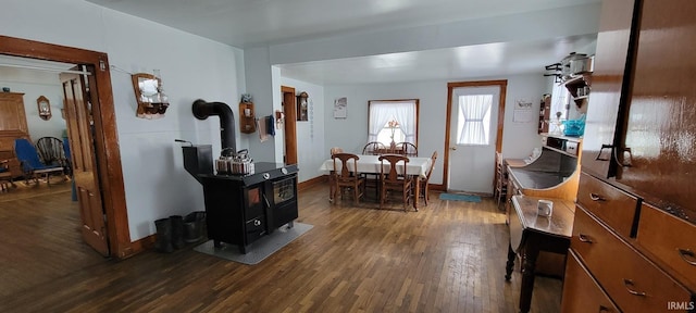 dining space with a wood stove, baseboards, and dark wood-type flooring