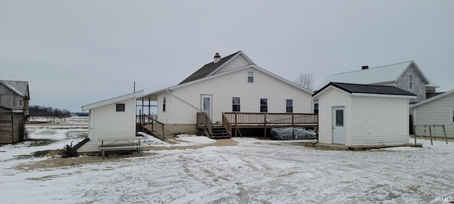 snow covered rear of property with metal roof and a wooden deck