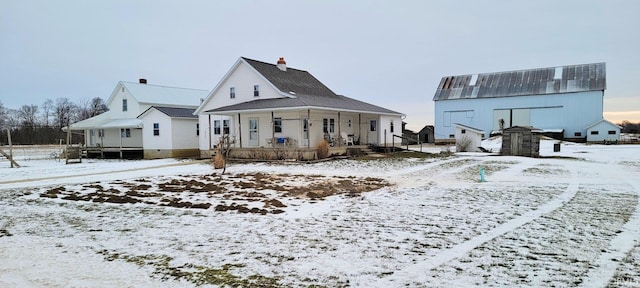 snow covered rear of property featuring a porch