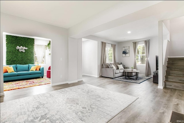 living area featuring baseboards, stairway, wood finished floors, and recessed lighting