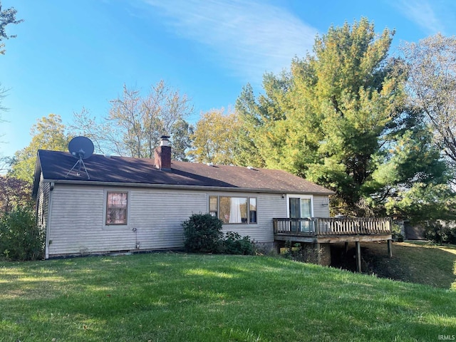 rear view of property with a chimney, a deck, and a yard