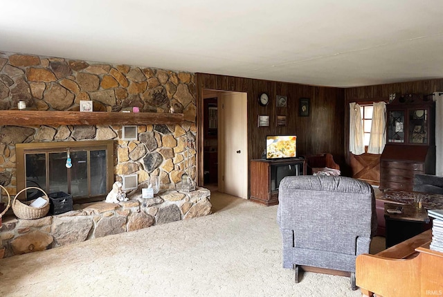 living room with light carpet, wooden walls, and a stone fireplace