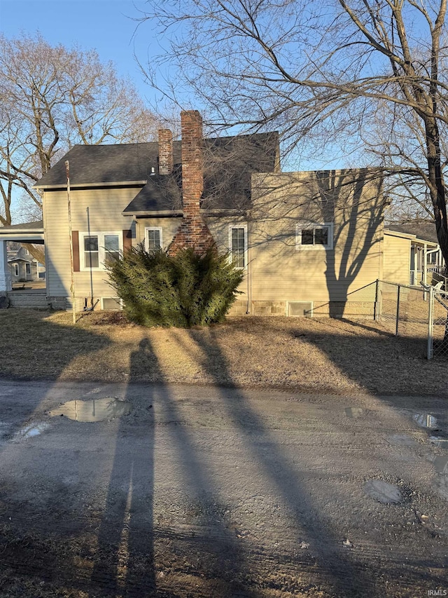 back of property featuring a carport, fence, and a chimney