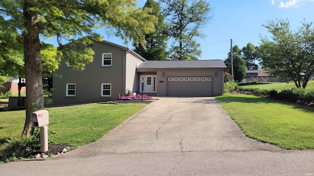 tri-level home featuring a front yard, driveway, an attached garage, and stucco siding