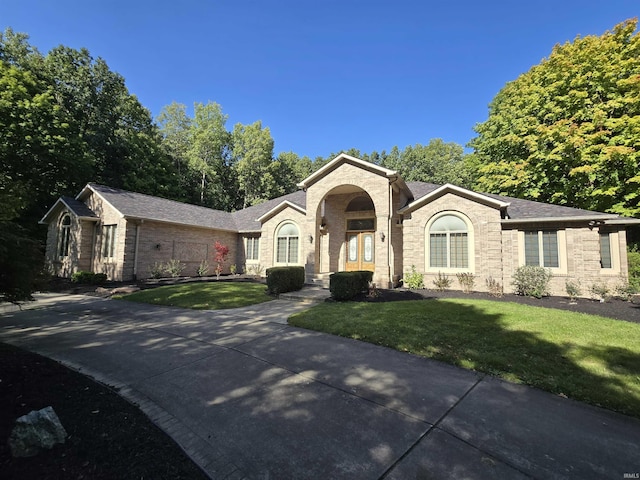 single story home with concrete driveway and a front yard