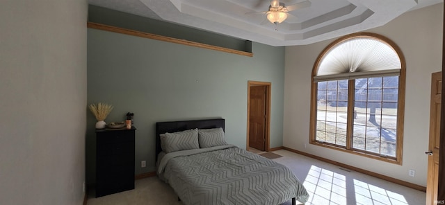 bedroom with light carpet, visible vents, a tray ceiling, and baseboards