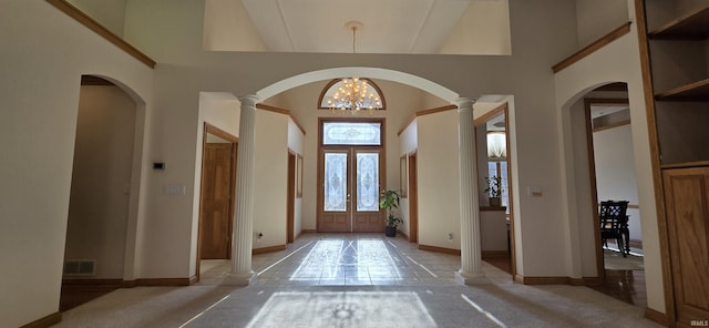 foyer entrance featuring visible vents, decorative columns, a towering ceiling, and a chandelier