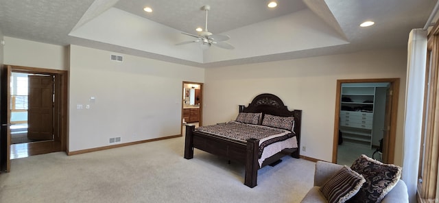 bedroom with baseboards, a raised ceiling, visible vents, and light colored carpet