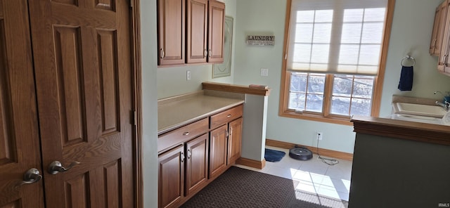 interior space featuring tile patterned flooring, a sink, and baseboards