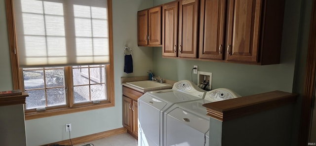 laundry area with light tile patterned floors, washing machine and dryer, a sink, baseboards, and cabinet space