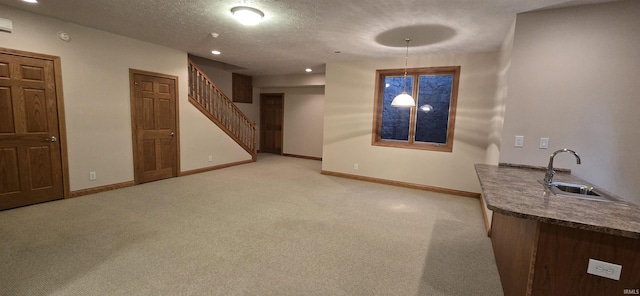 interior space featuring light carpet, baseboards, hanging light fixtures, a textured ceiling, and a sink