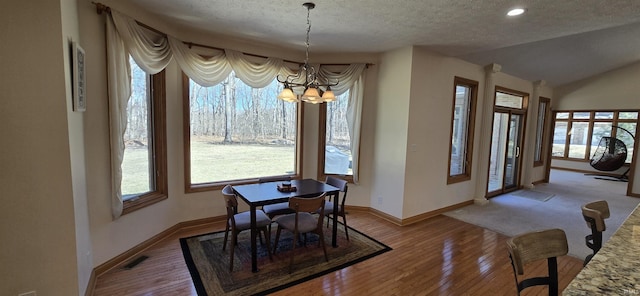 dining room featuring a chandelier, visible vents, vaulted ceiling, and hardwood / wood-style floors