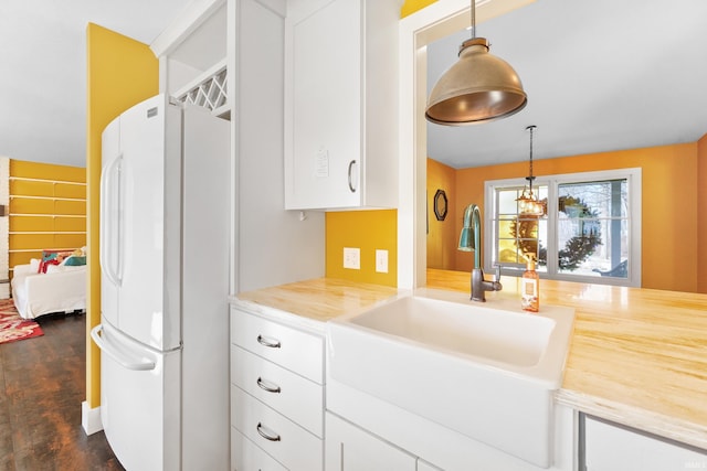 kitchen featuring hanging light fixtures, white cabinets, light countertops, and freestanding refrigerator