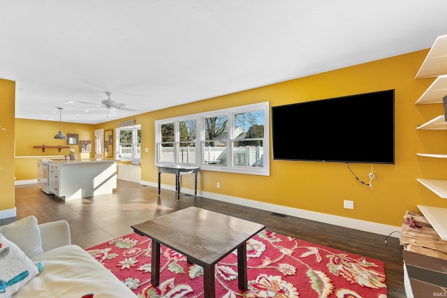 living area featuring visible vents, baseboards, and ceiling fan