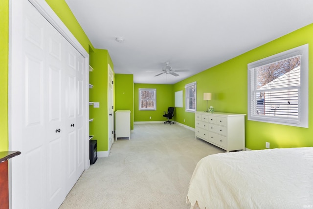 bedroom with a ceiling fan, baseboards, a closet, and light colored carpet