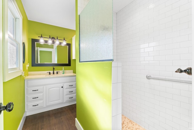 bathroom featuring wood finished floors, walk in shower, vanity, and baseboards