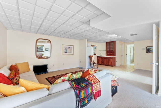 living area with light colored carpet, visible vents, and baseboards