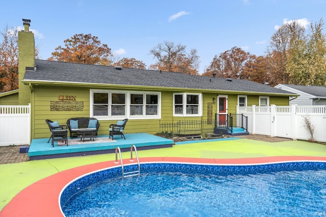 rear view of property with a shingled roof, a fenced in pool, a chimney, fence, and outdoor lounge area